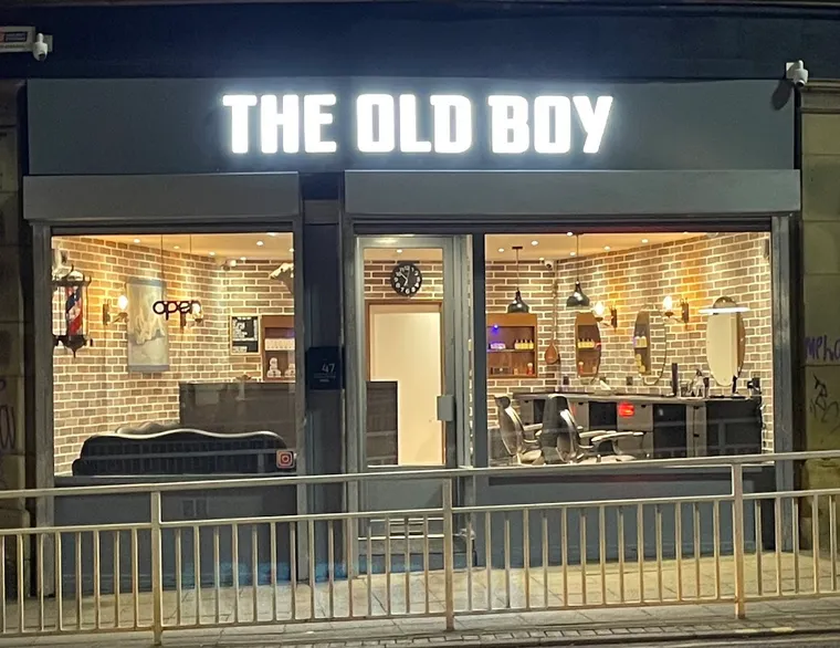 The Old Boy barbershop lit up at night on Church Street, Sheffield