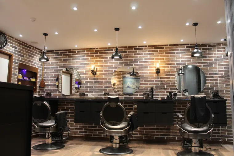 Inside The Old Boy — barber chairs along an exposed-brick wall under warm pendant lights