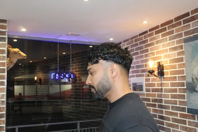 A curly crop finished with a clean fade, shot in the shop window