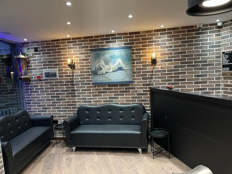 The waiting lounge at The Old Boy — chesterfield sofas against exposed brick